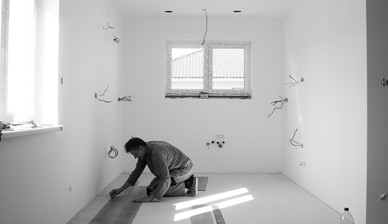 A contracting working on flooring of a house